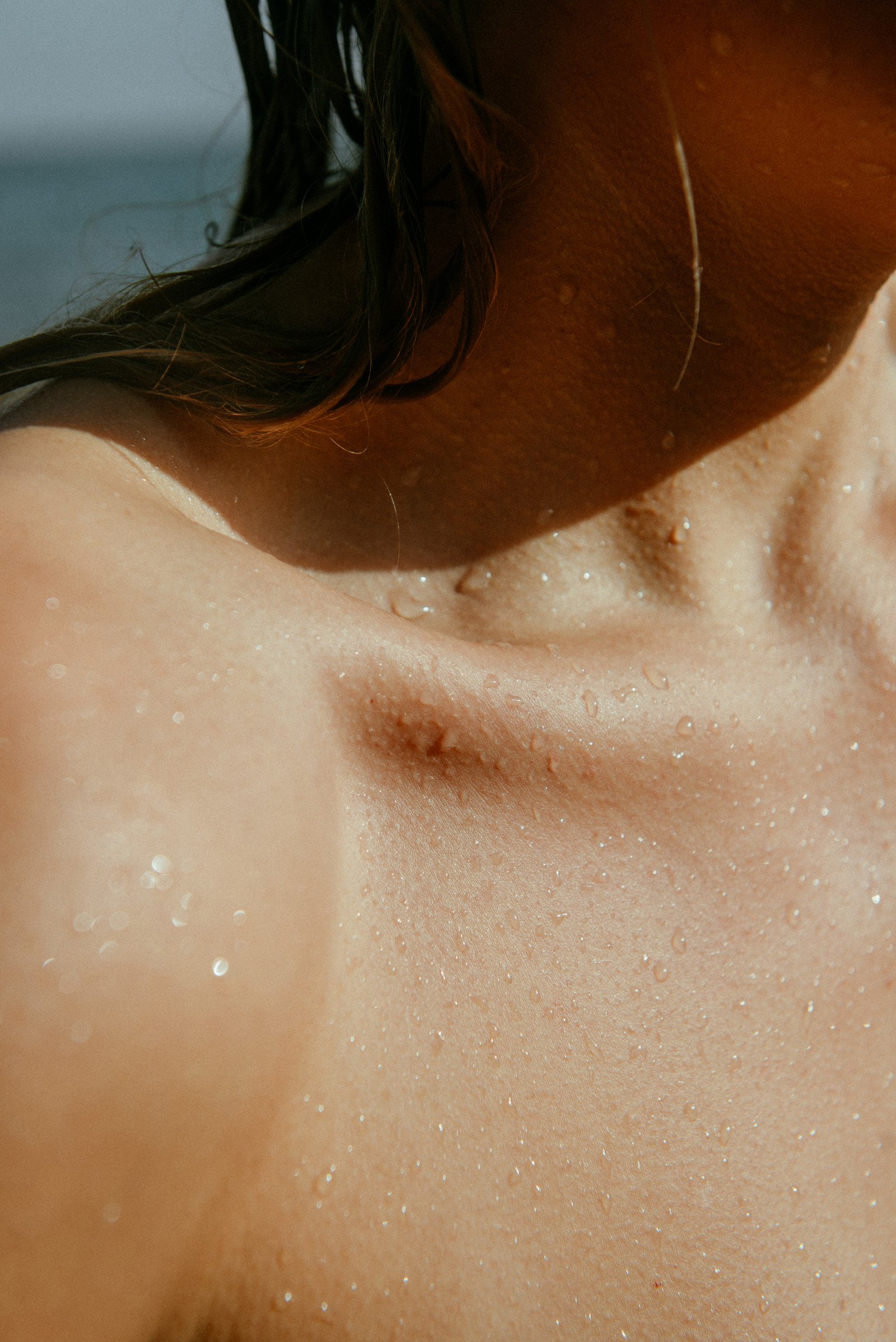 Close-up of a woman's neck and collarbone with water droplets on her skin